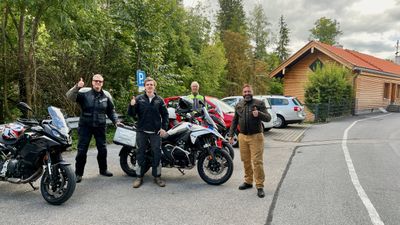 Riders stopped beside the bikes on a forested mountain road