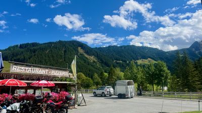 Mountain restaurant-pizzeria stop with bikes and a forested valley behind it