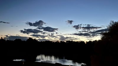 Hotel grounds at dusk, pond and trees behind the terrace lights