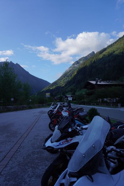 White BMW GS parked with more tour bikes and a mountain village behind