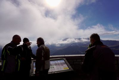 Riders at a Glockner overlook pointing into the clouded valley