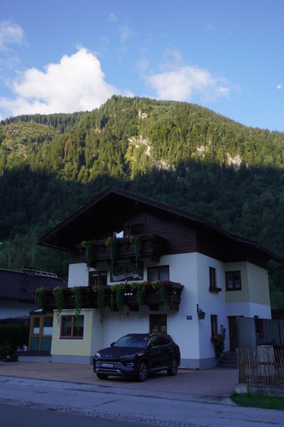 Flower-boxed alpine chalet in shade with sun on the mountain behind it