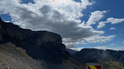 Sun breaking through cloud over scree and a Glockner cliff