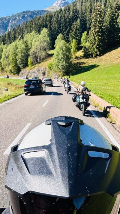 Looking over the windscreen at riders ahead on a tree-lined road