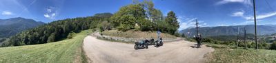 Panorama of a westbound mountain road through green fields