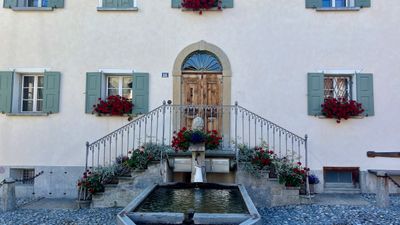 Stone fountain and flower boxes on a white house