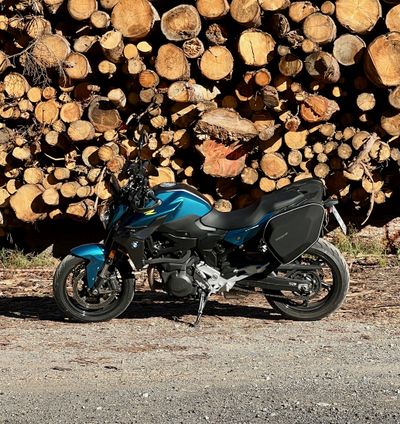 Teal touring bike parked in front of a wall of stacked logs