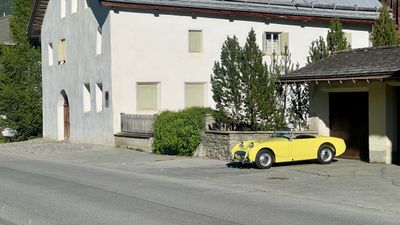 Yellow convertible parked against a stone building