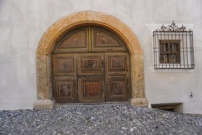 Heavy arched wooden door in a plaster wall