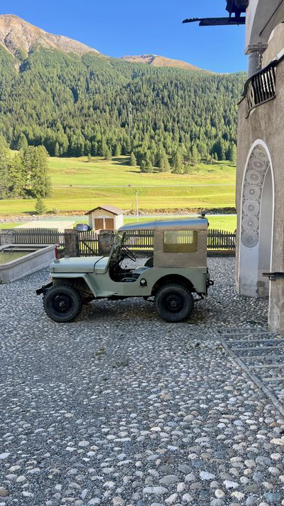 Vintage green jeep parked on cobblestones