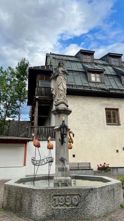 Plainplatzl fountain in Imst with flamingos and a statue of Mary